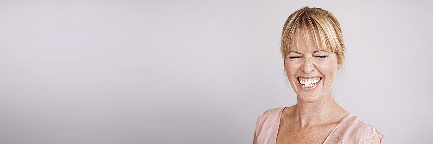 Herzhaft lachende Frau mit schönen, weißen Zähnen.